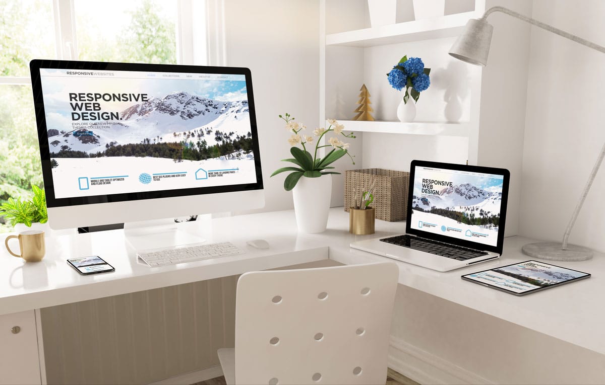 white desktop showing a website on large monitor, laptop monitor and tablet